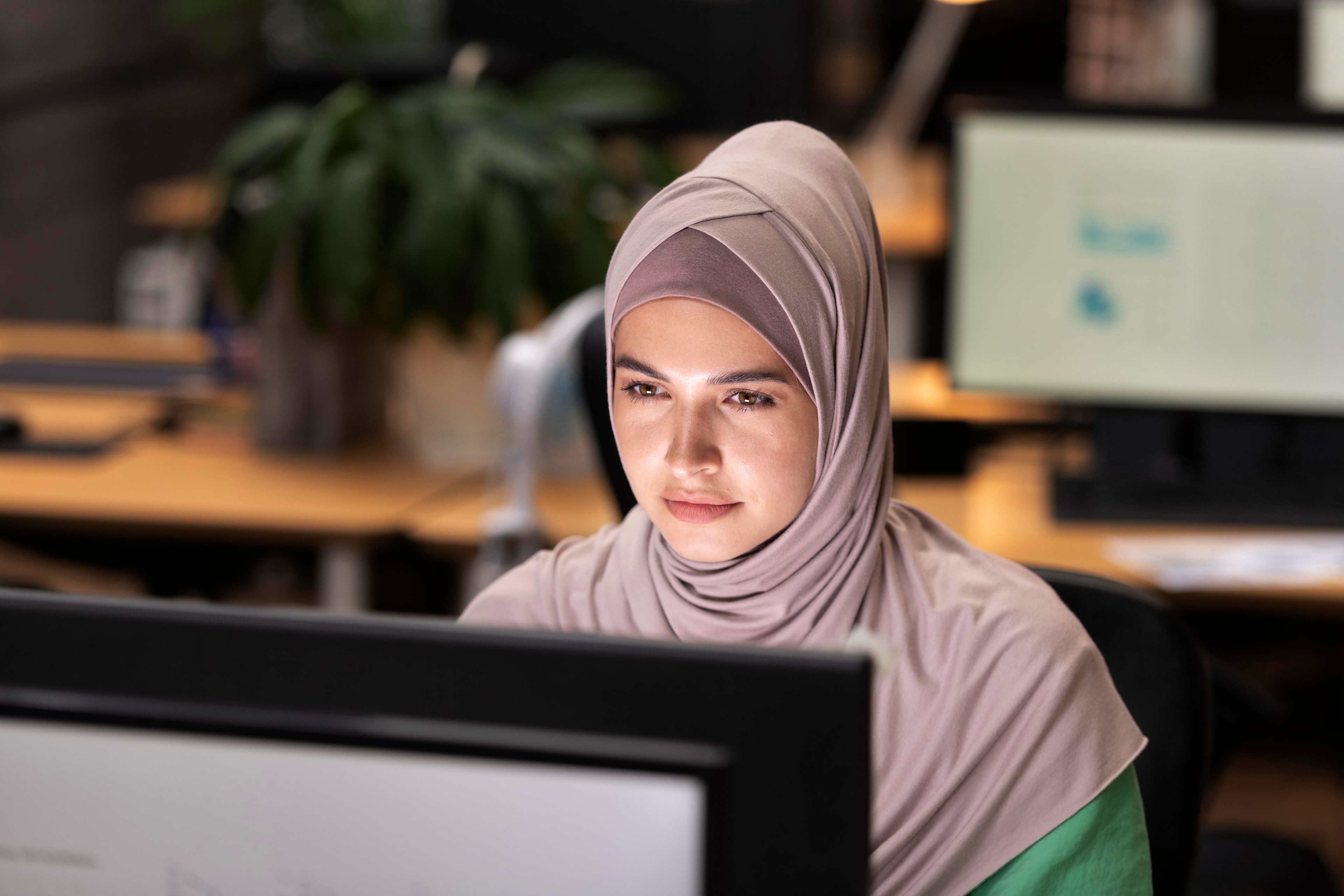 Afghan student typing on a laptop in a community space